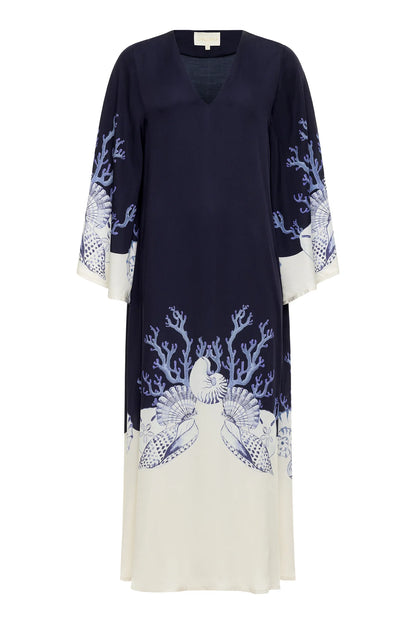 The Lena Kaftan by Carolina K is a navy and white long-sleeve dress featuring marine-inspired shell and coral prints along the hem and sleeves—a stunning artist collaboration with Felicity Buchanan.