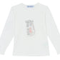 The Tartine et Chocolat Girls' Long-Sleeved Graphic T-Shirt features an ecru design with a Parisian-style illustration of a person walking by a building on the chest.