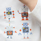 A boy wears the Tartine et Chocolat Baby Boys and Boys' Robots Illustration T-Shirt, featuring four colorful robot prints and the brand name below.