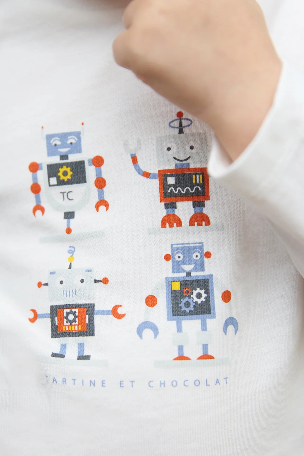 A boy wears the Tartine et Chocolat Baby Boys and Boys' Robots Illustration T-Shirt, featuring four colorful robot prints and the brand name below.