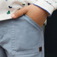 A child from our Tartine et Chocolat Baby Boys' and Boys' Trouser Pants range wears blue-grey trousers and a white patterned shirt, with their right hand tucked stylishly in their pocket.