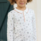 A young child with curly hair wears the Tartine et Chocolat Baby Boys' and Boys' Robots Illustration Long Sleeved Polo, standing before a dark green door.