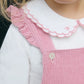 Close-up of a young child in Tartine et Chocolat’s Baby Girl’s Velvet Overalls in eglantine pink, featuring charming ruffle straps, worn over a white scallop-edged collared shirt.