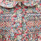 Close-up of the Girls' Liberty Smocked Floral Tunic by Tartine et Chocolat, showing smocked and embroidered details with a rounded collar at the top.