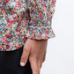 A close-up of a girl’s hand by her side, wearing the Tartine et Chocolat Girls' Liberty Smocked Floral Tunic with ruffled cuffs and black pants.