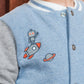 A child wears the Tartine et Chocolat Baby Boys' and Boys' Easy Bomber Cardigan in blue and grey, featuring embroidered robot, rocket, and planet designs.