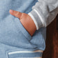 A boy wears the Tartine et Chocolat Baby Boys' and Boys' Easy Bomber Cardigan in light blue and gray with white trim, resting his hand in the front pocket.