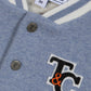 Close-up of Tartine et Chocolat's Baby Boys' and Boys' Easy Bomber Cardigan in blue and white, featuring metal snap buttons, a "TC" patch, and a size 3M label.