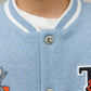 Close-up of a child in Tartine et Chocolat’s Baby Boys' and Boys' Easy Bomber Cardigan, light blue with white trim, metal snap buttons, and embroidered robot, planet, and "T" designs.