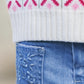 Close-up of Tartine et Chocolat Girls' Blue Flared Embroidery Jeans with floral detailing on the pocket, paired with a white knit sweater featuring a pink and green pattern.