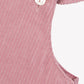 Close-up of Tartine et Chocolat Baby Girl's Velvet Overalls, designed in eglantine pink with delicate ruffles and two white buttons on the shoulder straps.