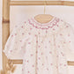 The Tartine et Chocolat Baby Girls' Ruffle Collar Embrodery Floral Dress, featuring delicate embroidery and long sleeves, is displayed on a wooden hanger against a bamboo rack.