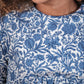A girl wears the Tartine et Chocolat Girls' Liberty Printed Dress in blue and white, smiling with only the lower half of her face visible.
