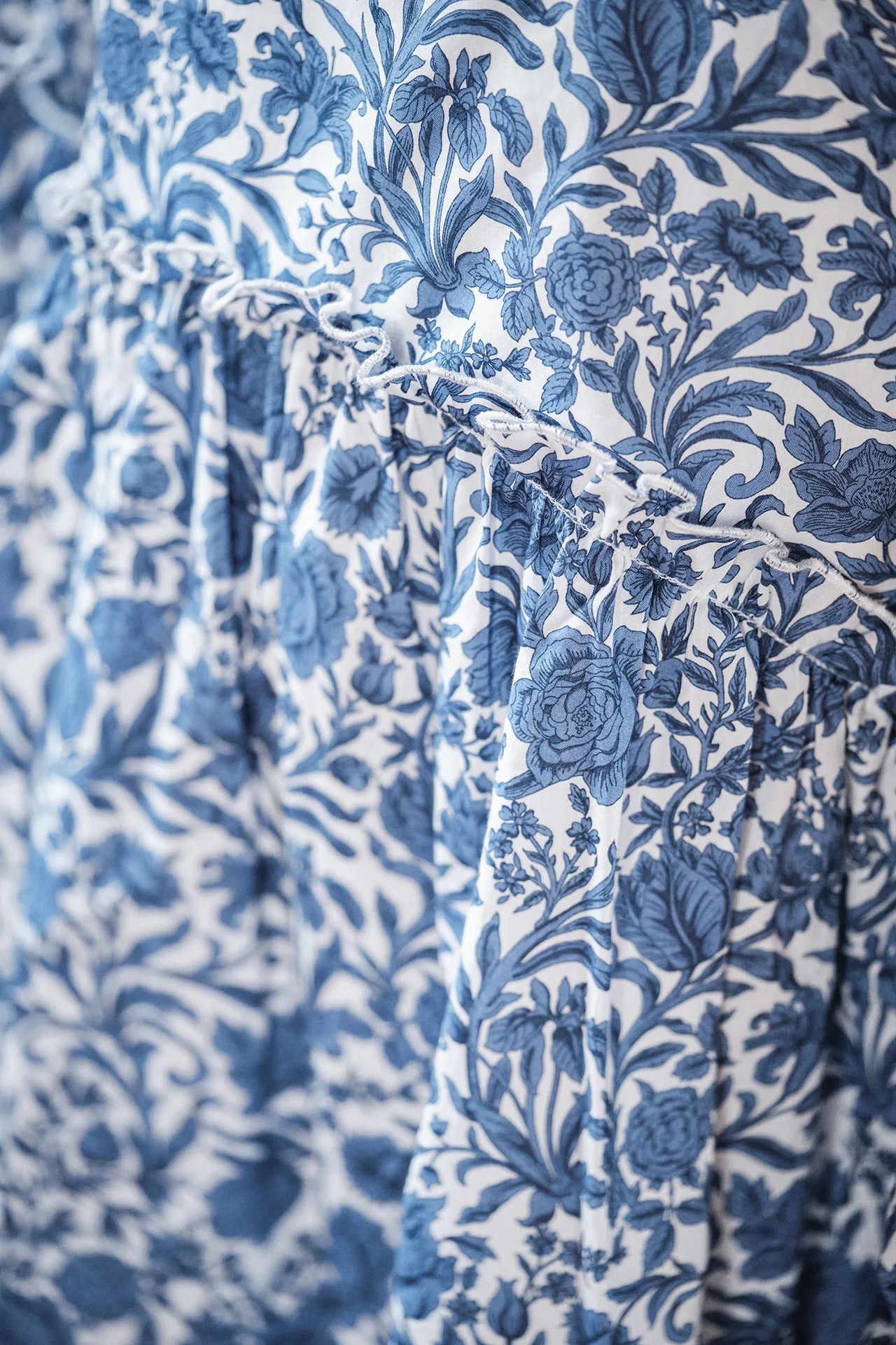 Close-up of the Tartine et Chocolat Girls' Liberty Printed Dress featuring a blue leafy pattern on white fabric, with delicate gathers and refined seams.