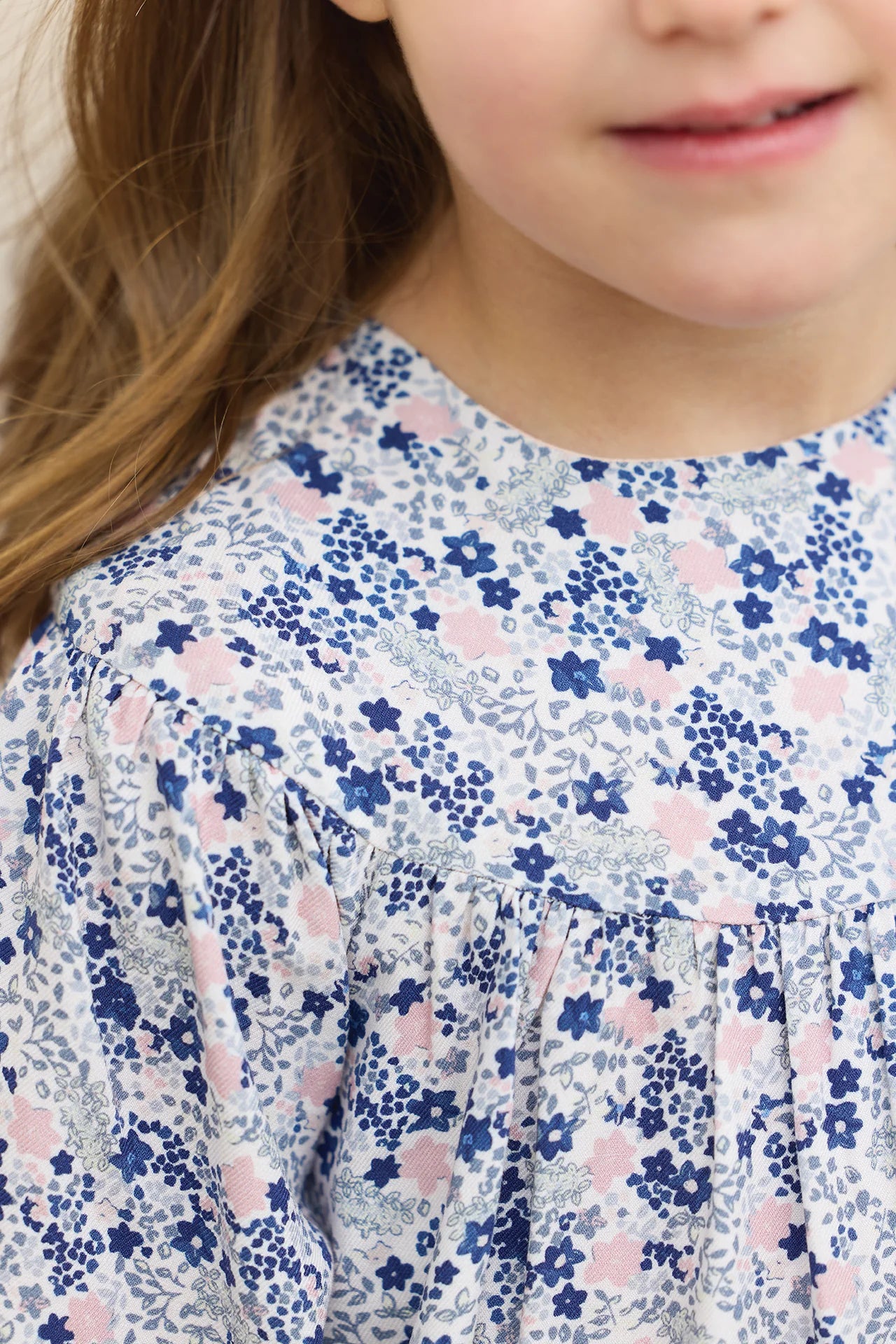 A young girl wears the Tartine et Chocolat Baby Girls' and Girls' Small Flower Blueberry Printed Dress. Only the lower half of her face and upper body are visible.
