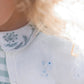 Close-up of a child in a green gingham dress and collared shirt, wearing the Tartine et Chocolat Baby Girls' Emeraude Embrodery Floral Cardigan, which beautifully complements her curly blond hair.
