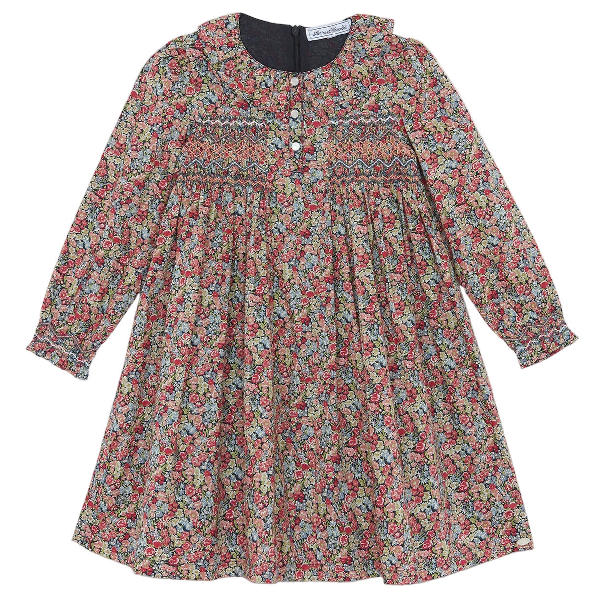 The Tartine et Chocolat Girls' Liberty Smocked Ruffle Sleeved Floral Dress features a vibrant Liberty print, smocked chest, ruffled sleeves and collar, plus front buttons for easy dressing.