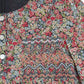 Close-up of Tartine et Chocolat’s Girls' Liberty Smocked Ruffle Sleeved Floral Dress, featuring smocking, silver buttons, and a visible brand label at the ruffled collar.
