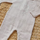 The Tartine et Chocolat Baby Boys' Embrodery Hedgehog Long Sleeved Jumpsuit in beige features a handmade hedgehog embroidery on the chest and is displayed on a woven mat.