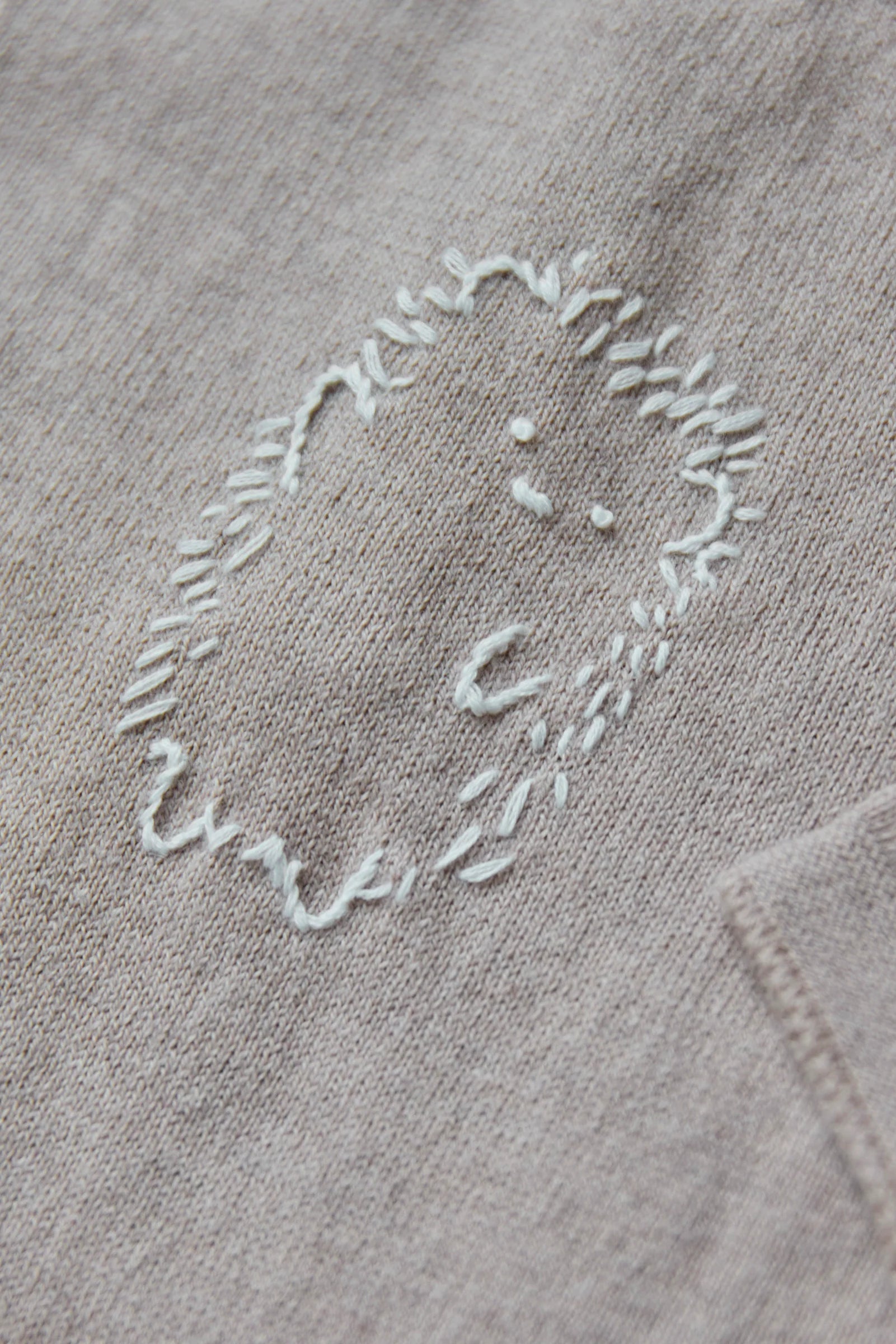 Close-up of the Tartine et Chocolat Baby Boys' Embrodery Hedgehog Long Sleeved Jumpsuit in beige, featuring a simple white handmade embroidered hedgehog outline.