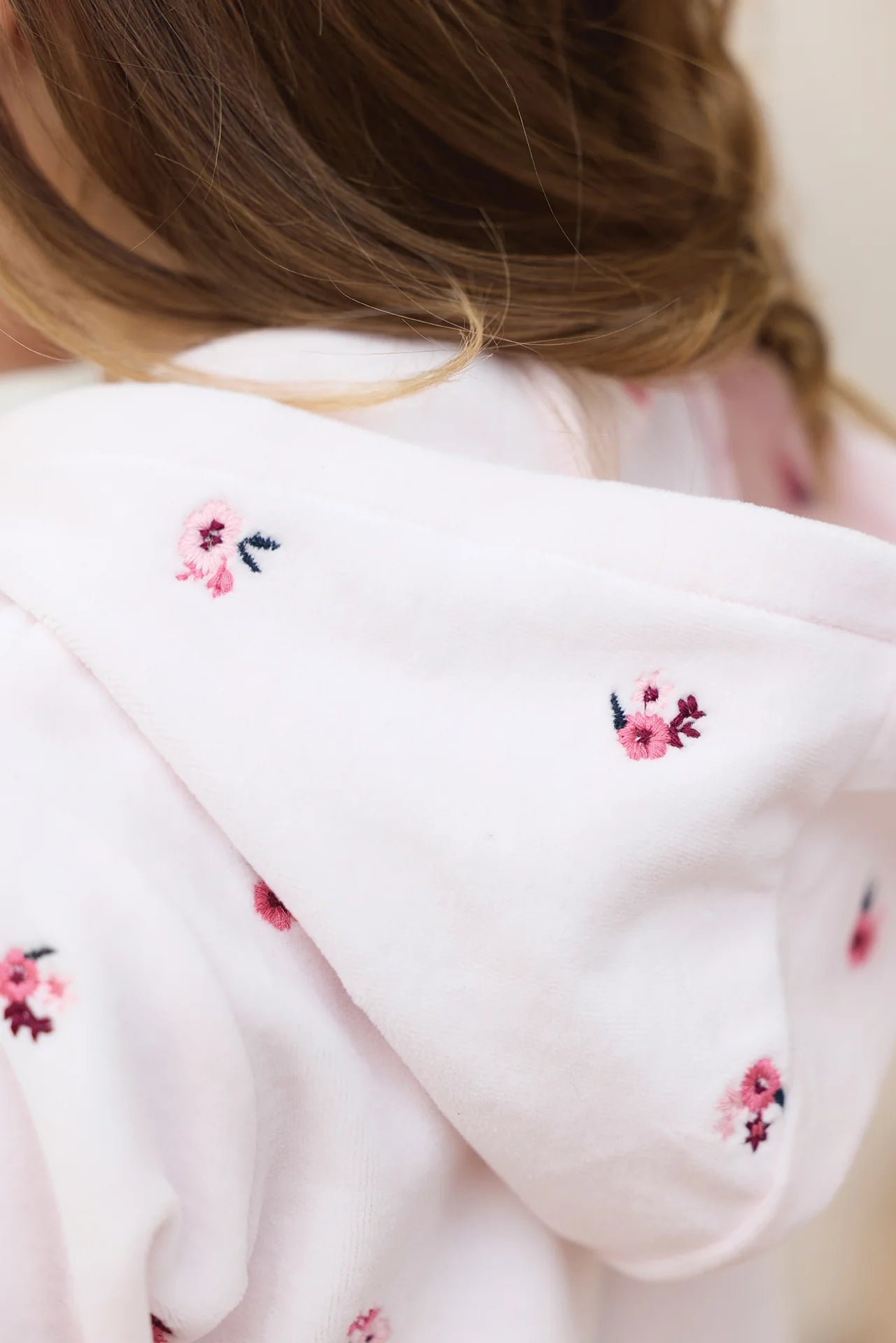 Close-up of a girl wearing the Tartine et Chocolat Baby Girls' and Girls' Velvet Hooded Jogger Set in light pink, featuring delicate embroidered floral details on the hood.