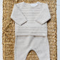 The Tartine et Chocolat Baby Long Sleeved Knit Outfit, featuring a beige sweater and matching pants in wool and cashmere, is displayed on a woven basket—a perfect winter choice for babies.