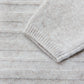 Close-up of the Tartine et Chocolat Baby Long Sleeved Knit Outfit in light gray, showing a sleeve and horizontal ribbed knit texture.