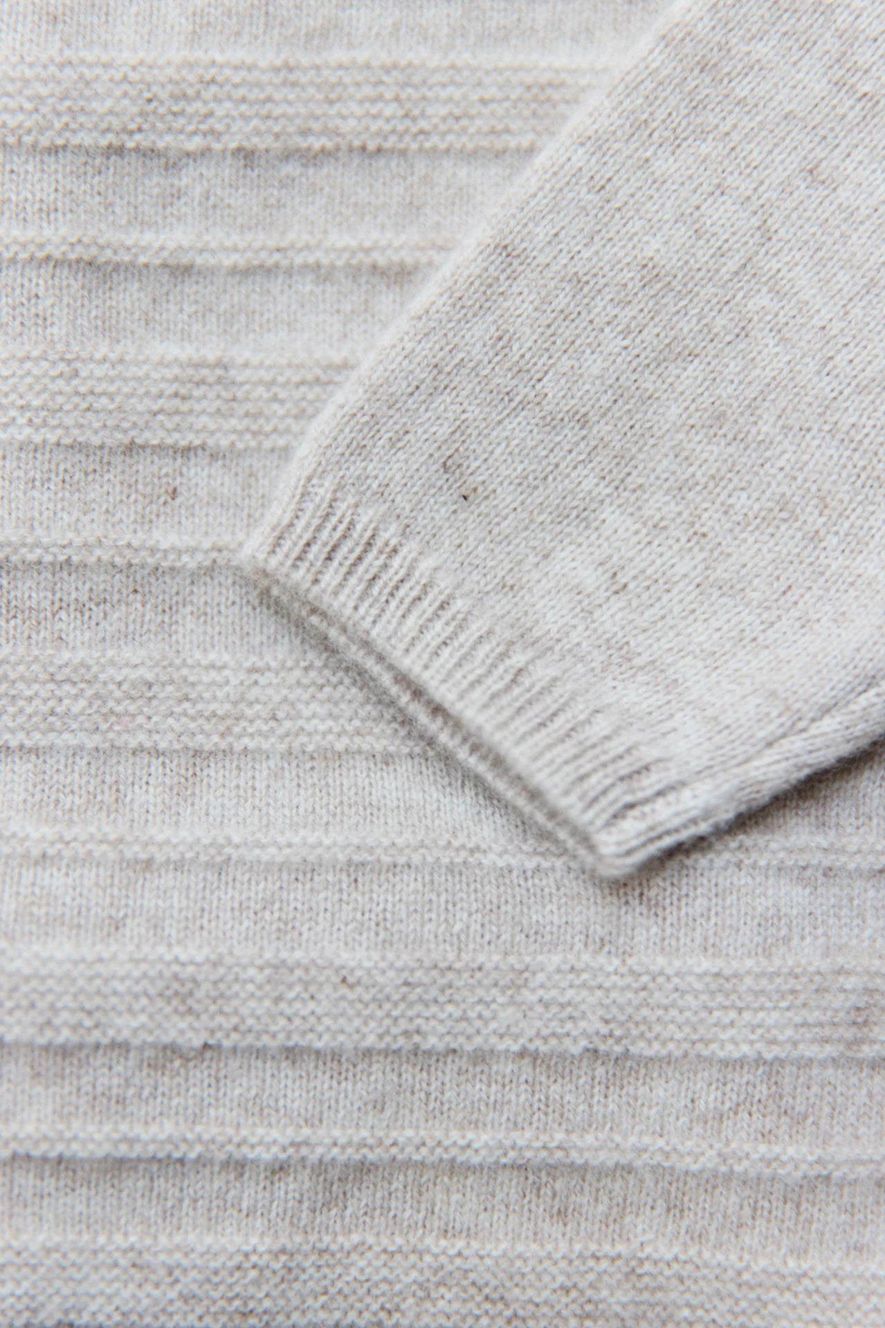 Close-up of the Tartine et Chocolat Baby Long Sleeved Knit Outfit in light gray, showing a sleeve and horizontal ribbed knit texture.