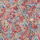 Close-up of Tartine et Chocolat's Girls' Liberty Fabric Down Jacket, featuring a red, blue, and cream floral print, gold button detail, and visible chest pocket stitching.