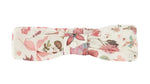 The Tartine et Chocolat Headband is a soft baby accessory in white fabric with a pink and green floral print and a central button detail—a charming printed headband for little ones.