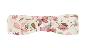 The Tartine et Chocolat Headband is a soft baby accessory in white fabric with a pink and green floral print and a central button detail—a charming printed headband for little ones.