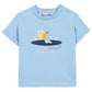 The Baby Boys’ and Boys’ Illustrated Cotton T-Shirt by Tartine et Chocolat features a light blue, 100% cotton fabric adorned with a playful graphic of a pelican and seagulls perched on a surfboard—an ideal choice for little explorers. The brand name “Tartine et Chocolat” is printed below the illustration.