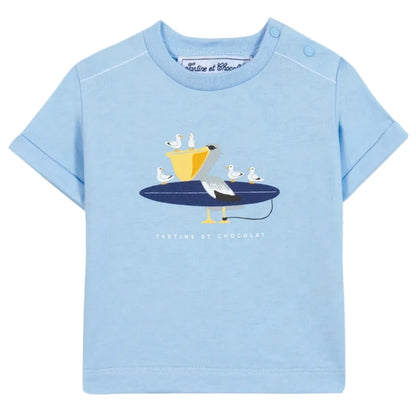 The Baby Boys’ and Boys’ Illustrated Cotton T-Shirt by Tartine et Chocolat features a light blue, 100% cotton fabric adorned with a playful graphic of a pelican and seagulls perched on a surfboard—an ideal choice for little explorers. The brand name “Tartine et Chocolat” is printed below the illustration.
