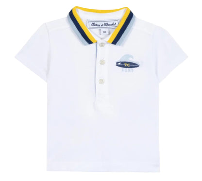 The Tartine et Chocolat Baby Boys’ and Boys’ Polo Shirt is a white cotton polo featuring a blue and yellow striped collar, three buttons, and a small embroidered surfboard logo on the left chest.