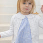 A young child with light brown hair stands in front of light-colored steps, wearing the Tartine et Chocolat Baby Girls’ and Girls’ Openwork Cardigan over a blue striped dress—showcasing the perfect lightweight layering piece for any occasion.