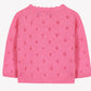 The Baby Girls’ and Girls’ Openwork Cardigan by Tartine et Chocolat features a pink knit design with small, evenly spaced heart-shaped eyelet patterns and long sleeves, displayed on a white background—a perfect layering piece that exudes delicate charm.