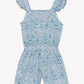 The Girls’ Liberty Print Short Jumpsuit by Tartine et Chocolat features scalloped edges at the shoulders and shorts, with a delicate small floral print in blue, green, and pink on a white background.