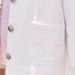 Close-up of the Tartine et Chocolat Girls’ Cotton Jacket in white, featuring floral embroidery on the pocket, ruffled edging, and brown buttons—shown as part of a matching outfit.