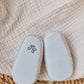 A pair of Tartine et Chocolat Baby Girls’ Liberty Fabric Espadrille Slippers with textured white soles rest on a cream-colored blanket and woven mat.