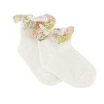 A pair of Tartine et Chocolat Baby Liberty Print Socks in white cotton, featuring a delicate floral ruffled trim around the ankle, displayed on a plain white background. These charming socks add a touch of sweetness to any little one’s outfit.