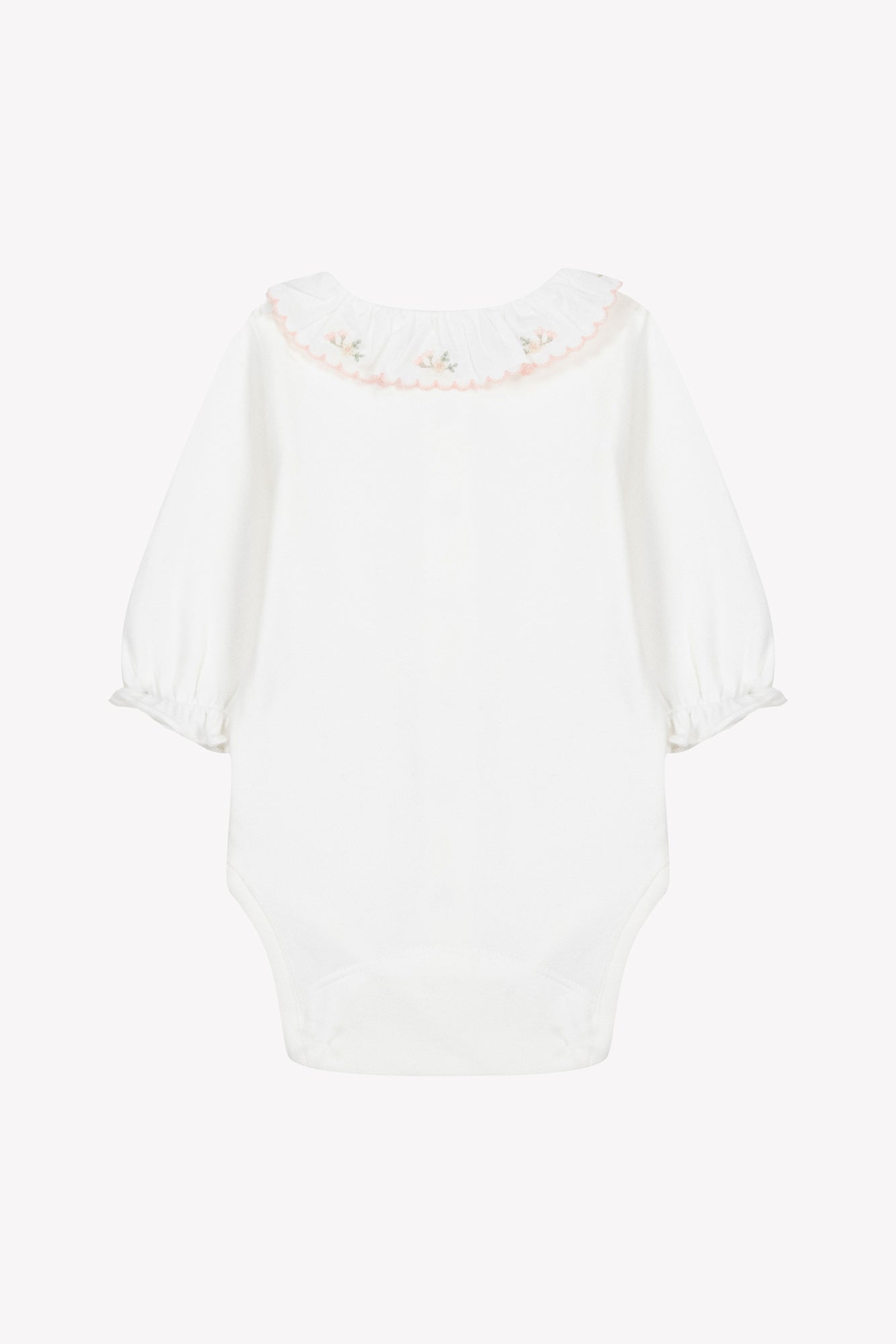 The Tartine et Chocolat Baby Girls’ Ruffled Collar Bodysuit is an ecru cotton long sleeve onesie, adorned with a ruffled floral collar accented by pink trim and delicate embroidered flowers, displayed flat against a plain background.