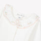 The Tartine et Chocolat Baby Girls’ Ruffled Collar Bodysuit features ecru white cotton with long sleeves and a ruffled floral collar adorned with pink embroidered flowers.