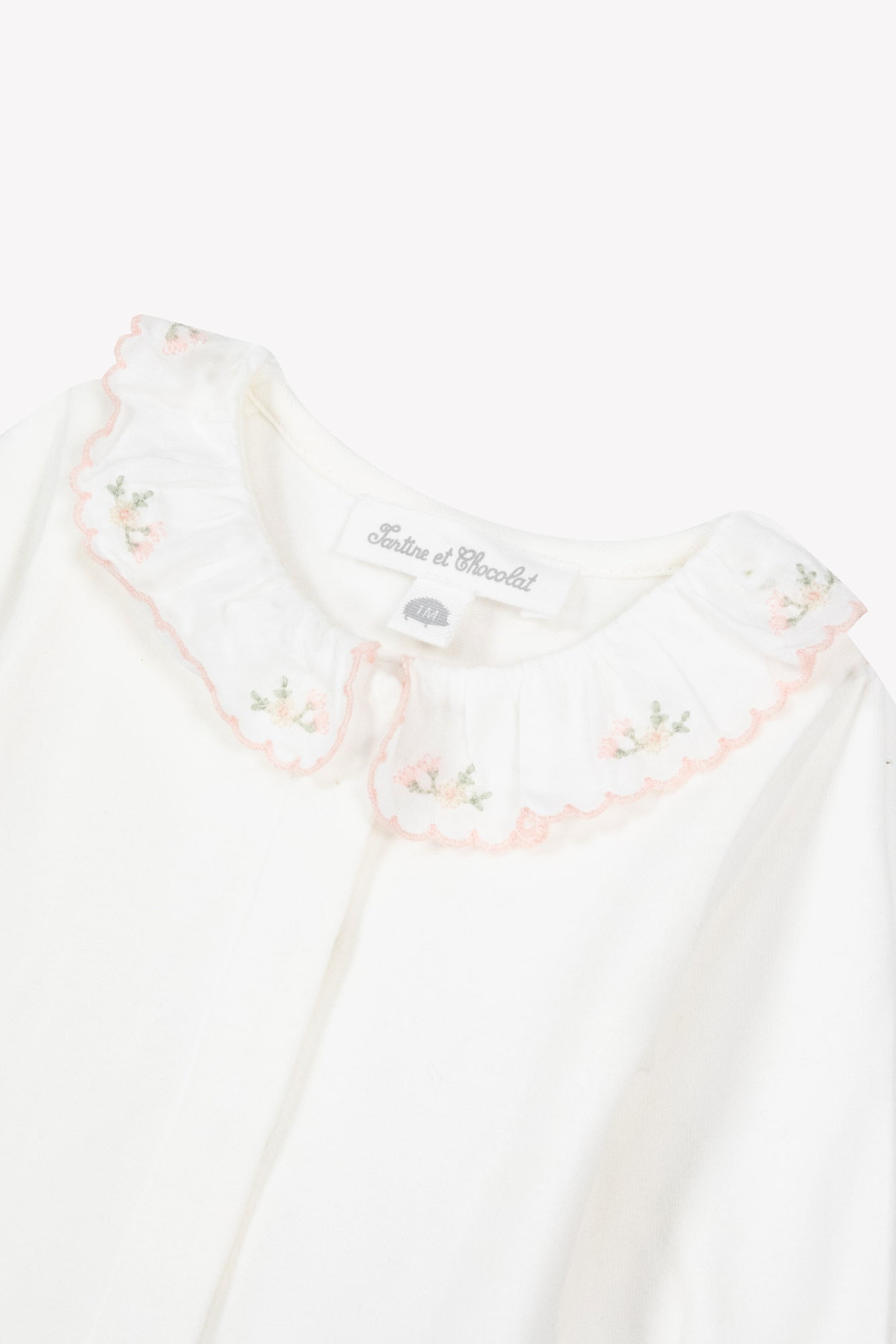 The Tartine et Chocolat Baby Girls’ Ruffled Collar Bodysuit features ecru white cotton with long sleeves and a ruffled floral collar adorned with pink embroidered flowers.