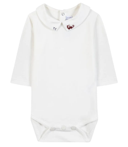 The Tartine et Chocolat Baby Boys’ Dinosaur Bodysuit features a white long-sleeve cotton design with a Peter Pan collar, button closure at the back, and snap buttons at the bottom; an embroidered red dinosaur on the collar adds a playful touch to this adorable baby romper.