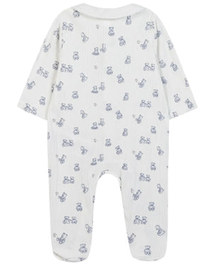 Introducing the Tartine et Chocolat Baby Boys’ Ribbed Knit Pajama—a white, long-sleeved onesie with covered feet, made from soft unbleached cotton. This pajama features an all-over pattern of small blue teddy bear motifs and baby accessories. The garment is displayed flat with the back facing up.