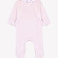 Tartine et Chocolat Baby Girls’ Velvet Peter Pan Collar Pajamas in light pink, featuring long sleeves with ruffled cuffs and an elegant white Peter Pan collar adorned with delicate pink embroidery. Presented flat on a white background, these pajamas offer convenient snap closures for easy changing while ensuring a cozy and refined look.
