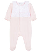 The Tartine et Chocolat Baby Girls’ Peter Pan Collar Gathered Pajamas feature a light pink long-sleeve footed design crafted from soft cotton, adorned with a charming white ruffled Peter Pan collar and a decorative panel across the chest with small pink dots and scalloped trim—an adorable choice for baby girls’ sleepwear.