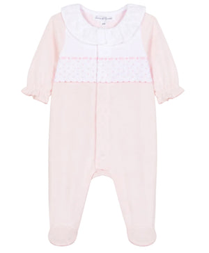 The Tartine et Chocolat Baby Girls’ Peter Pan Collar Gathered Pajamas feature a light pink long-sleeve footed design crafted from soft cotton, adorned with a charming white ruffled Peter Pan collar and a decorative panel across the chest with small pink dots and scalloped trim—an adorable choice for baby girls’ sleepwear.