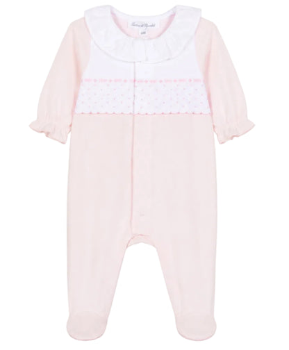 The Tartine et Chocolat Baby Girls’ Peter Pan Collar Gathered Pajamas feature a light pink long-sleeve footed design crafted from soft cotton, adorned with a charming white ruffled Peter Pan collar and a decorative panel across the chest with small pink dots and scalloped trim—an adorable choice for baby girls’ sleepwear.