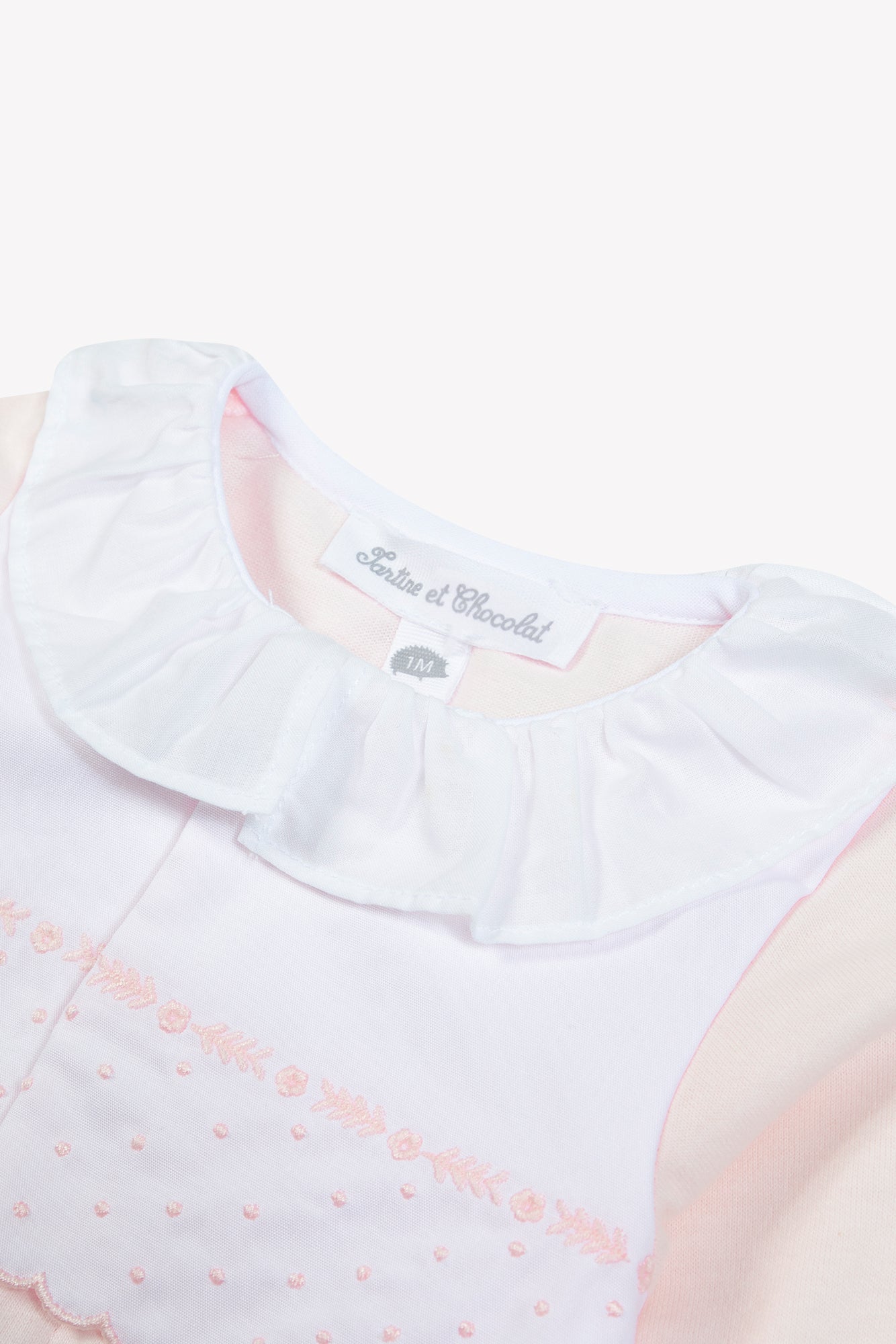 Close-up of the Baby Girls’ Peter Pan Collar Gathered Pajamas by Tartine et Chocolat, crafted from soft cotton and featuring a white ruffled Peter Pan collar, delicate pink embroidered details, and a visible “Tartine et Chocolat” label.